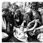 After giving care for a scalp wound, a Japanese baby is cared for by men a medical unit of the 27th Infantry Division.