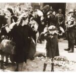 Jewish woman, some holding children in their arms, wait in line before they are ex3cuted by the Ukrainian police.