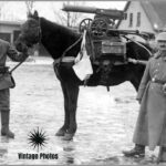 In a photograph from World War I, German soldiers pose proudly beside a horse-mounted frame designed to carry a captured Russian Maxim M1910 machine gun, complete with its original wheeled mount and ammunition box.