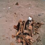 Mummy amongst cloth and artefacts in a desert, Peru :